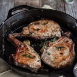 Cast iron skillet pork chops presented for service right out of the skillet - rustic family style!